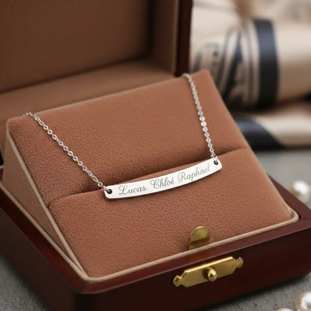 Collier gravé avec les prénoms des enfants posé sur un écrin élégant